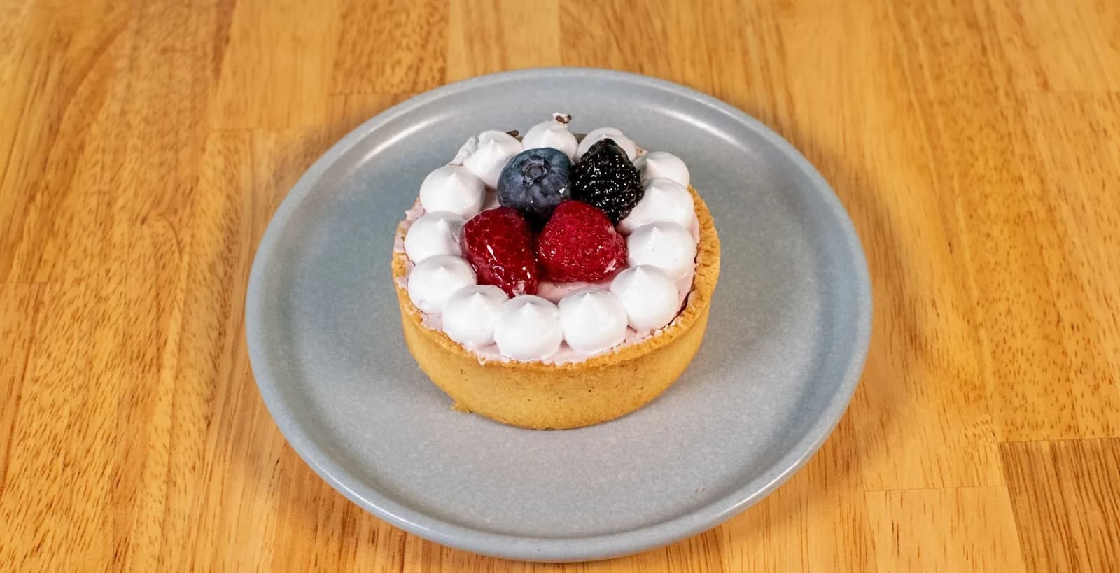 Mini tartelete com chantilly, framboesas e mirtilo em prato cinza