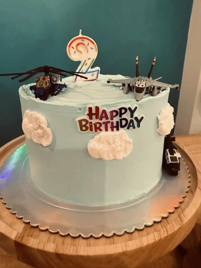 Blue birthday cake decorated with airplanes and clouds