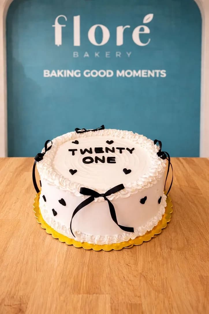 White twenty-first birthday cake with black bows and piped borders