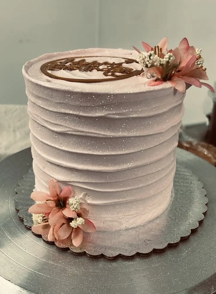Tall blush pink cake with floral accents and textured buttercream