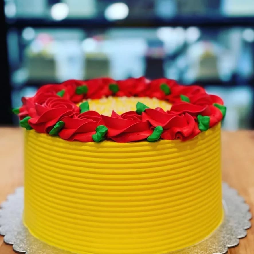 Yellow celebration cake finished with red buttercream roses