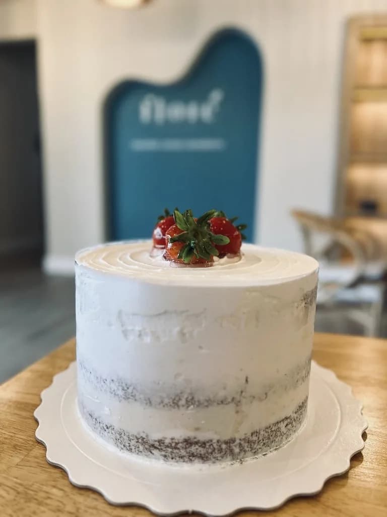 Minimalist white layer cake topped with fresh strawberries