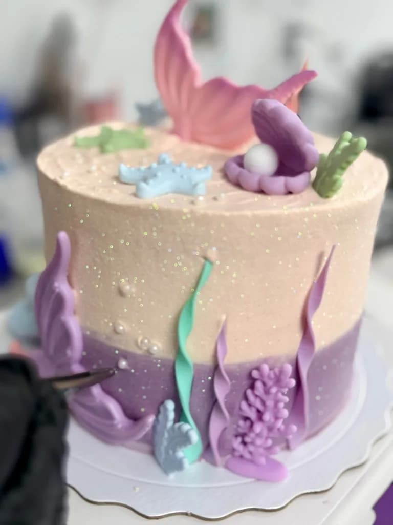 Pastel undersea-themed cake with shells and mermaid-tail decorations