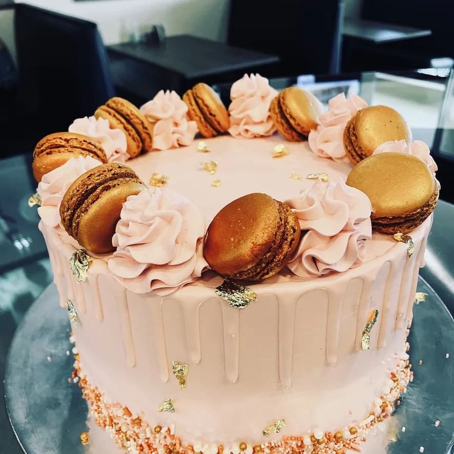 Blush pink celebration cake decorated with gold macarons