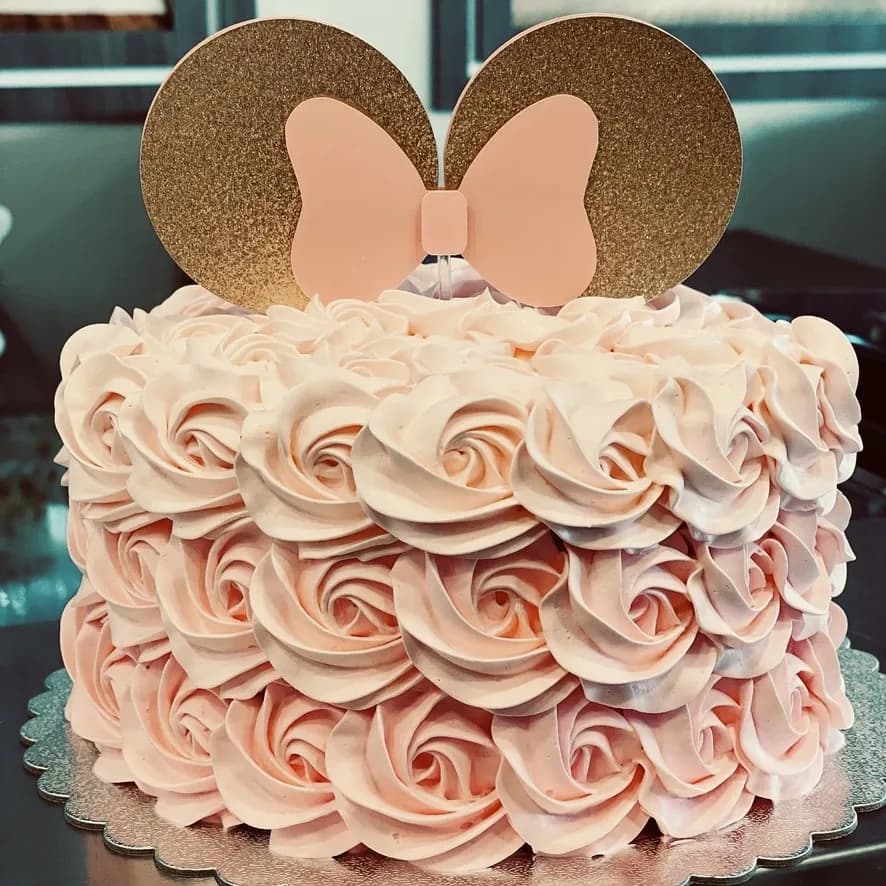 Pink rosette cake with mouse-ear and bow topper