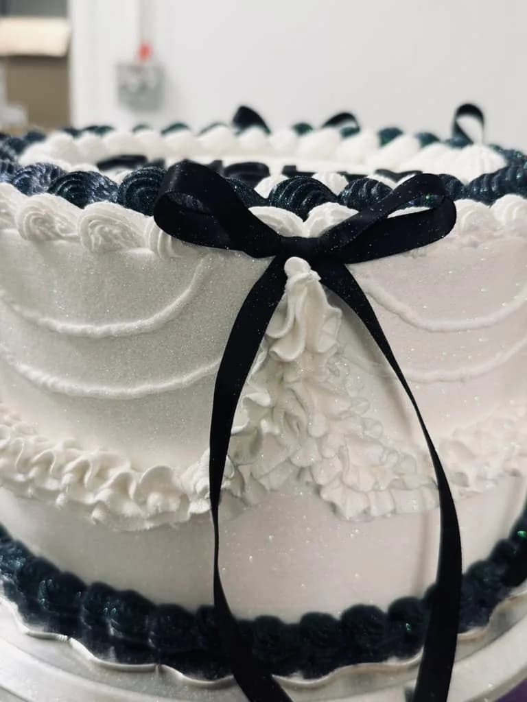 White vintage-style cake with black piping and ribbon detail
