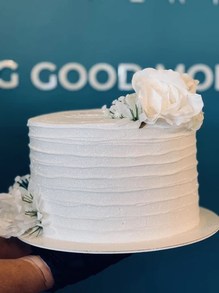 White textured celebration cake decorated with white roses