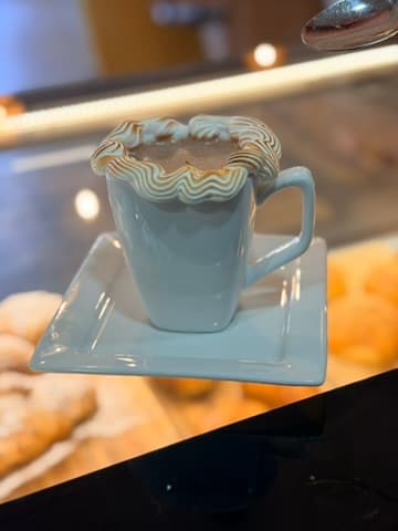 Café servido em xícara azul-clara no balcão da Floré