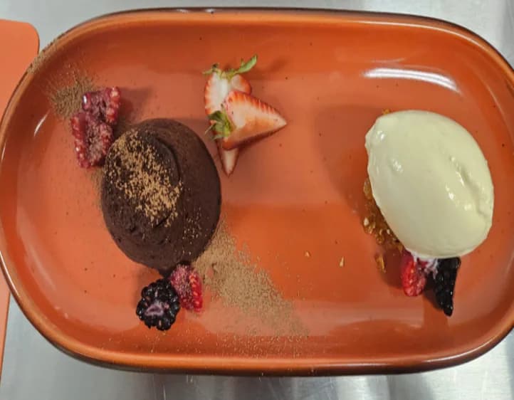 Petit gâteau com sorvete e frutas vermelhas em prato terracota