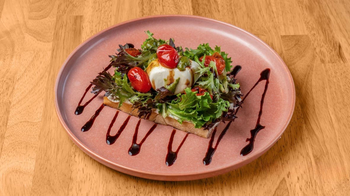 Floré Italy Toast with burrata, baby greens, confit tomatoes and balsamic reduction